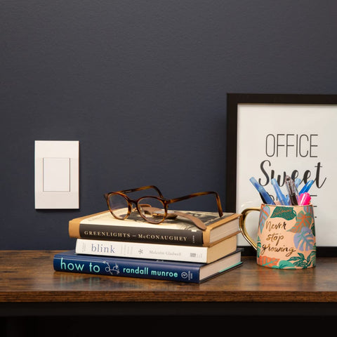 Deako Smart switch on a wall next to some books on a table